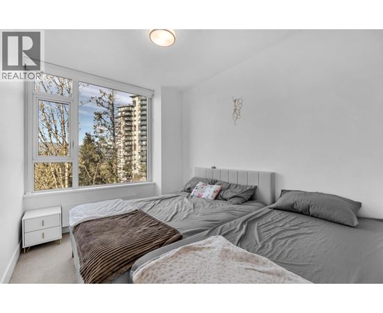 A bedroom with a large bed and a window overlooking a cityscape.