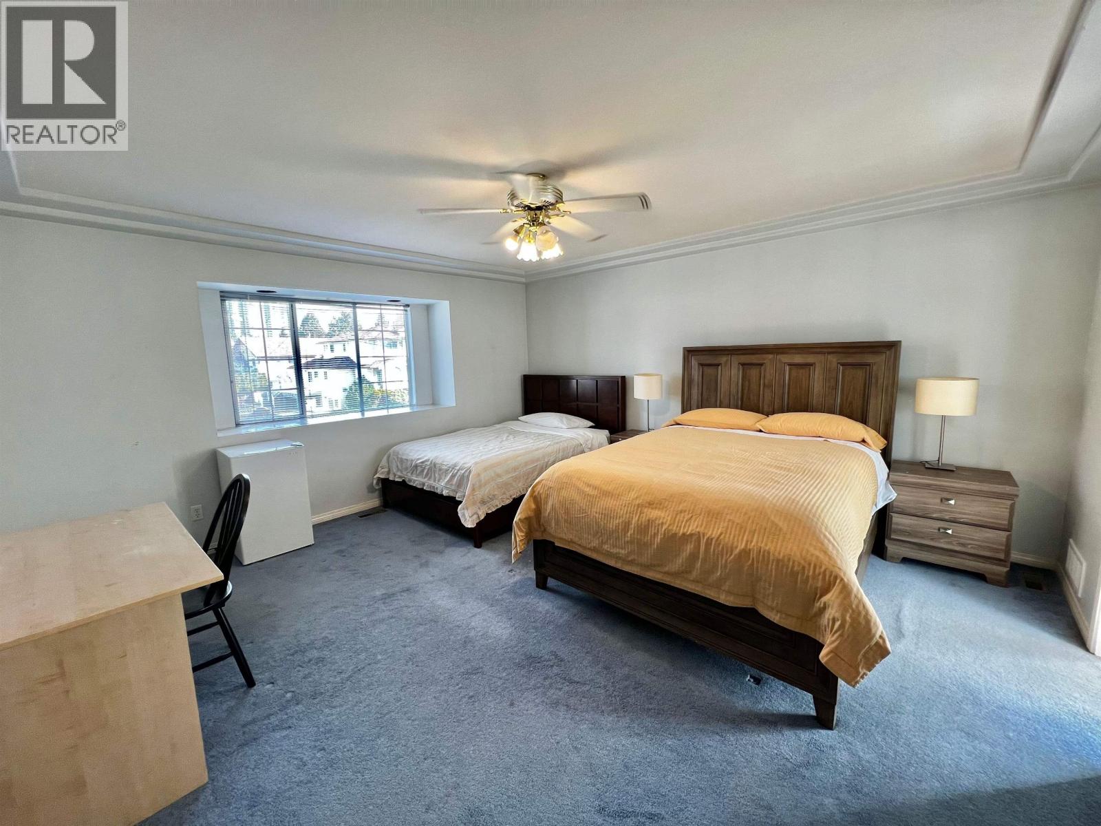 A bedroom with two beds and a ceiling fan.