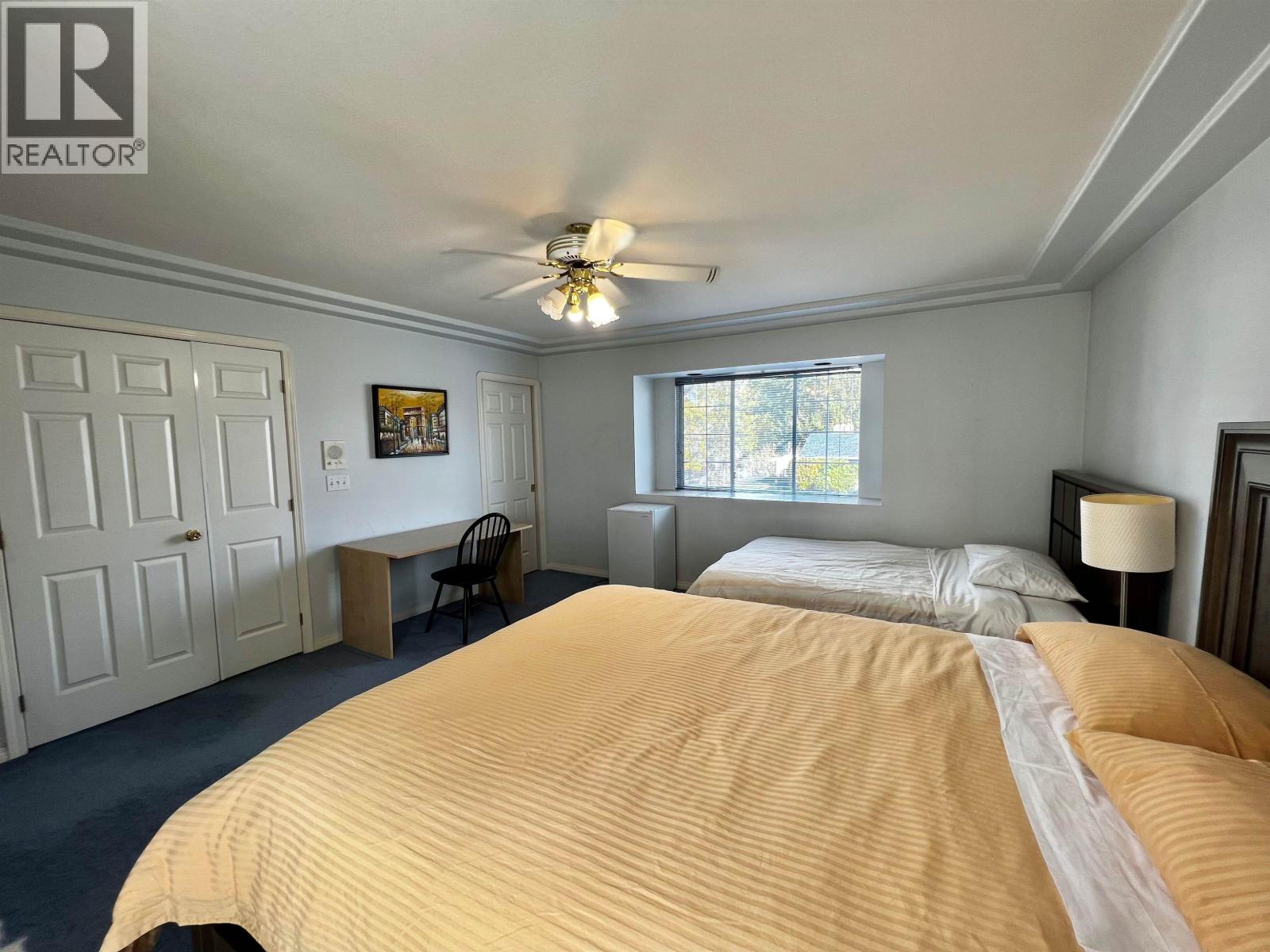 A bedroom with a large bed and a ceiling fan.