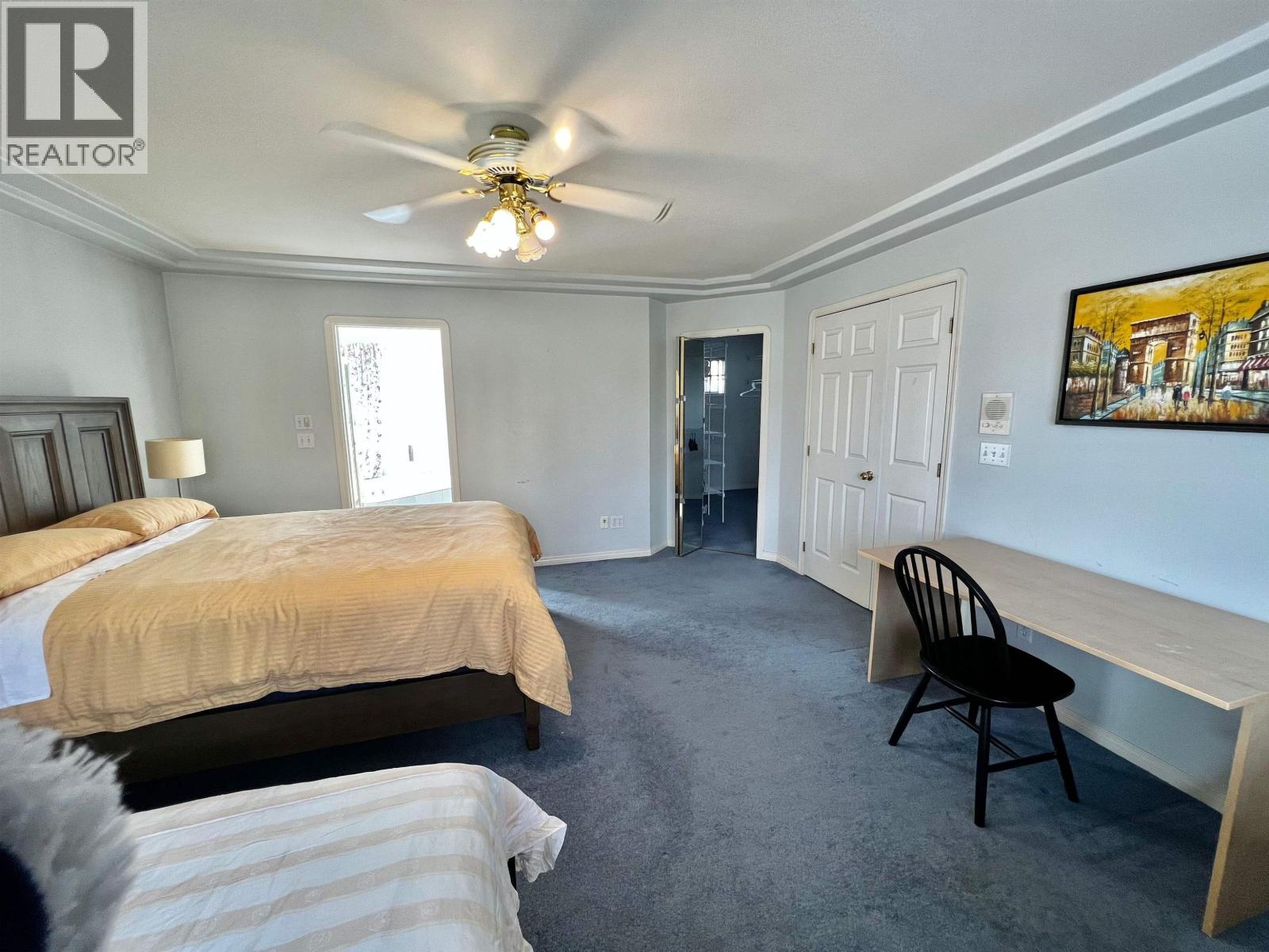 A bedroom with two beds and a ceiling fan.
