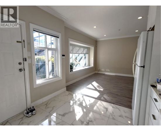 A spacious kitchen with white marble flooring and a refrigerator on the right side.