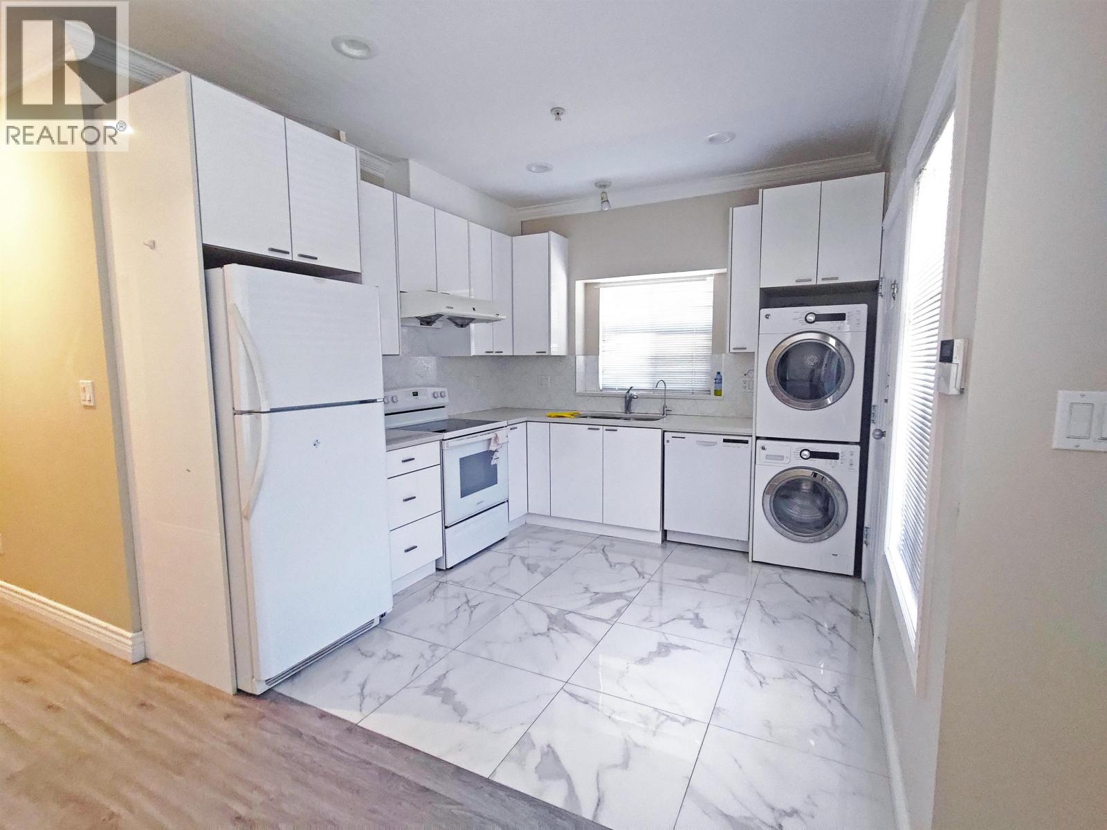 A white kitchen with a refrigerator, washing machine, and dishwasher.