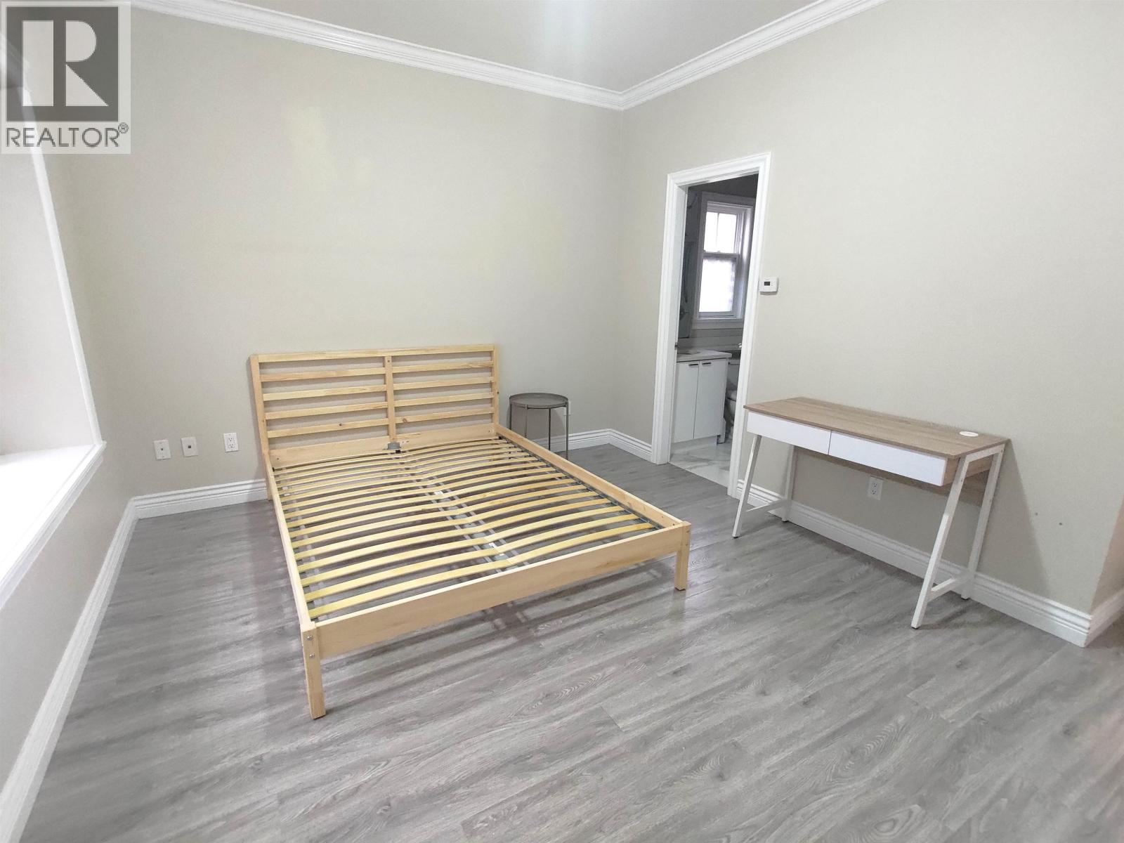 A bedroom with a bed, nightstand, and desk.