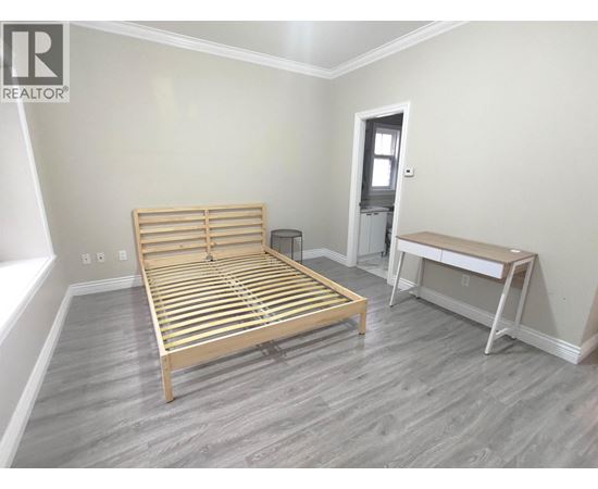 A bedroom with a bed, nightstand, and desk.
