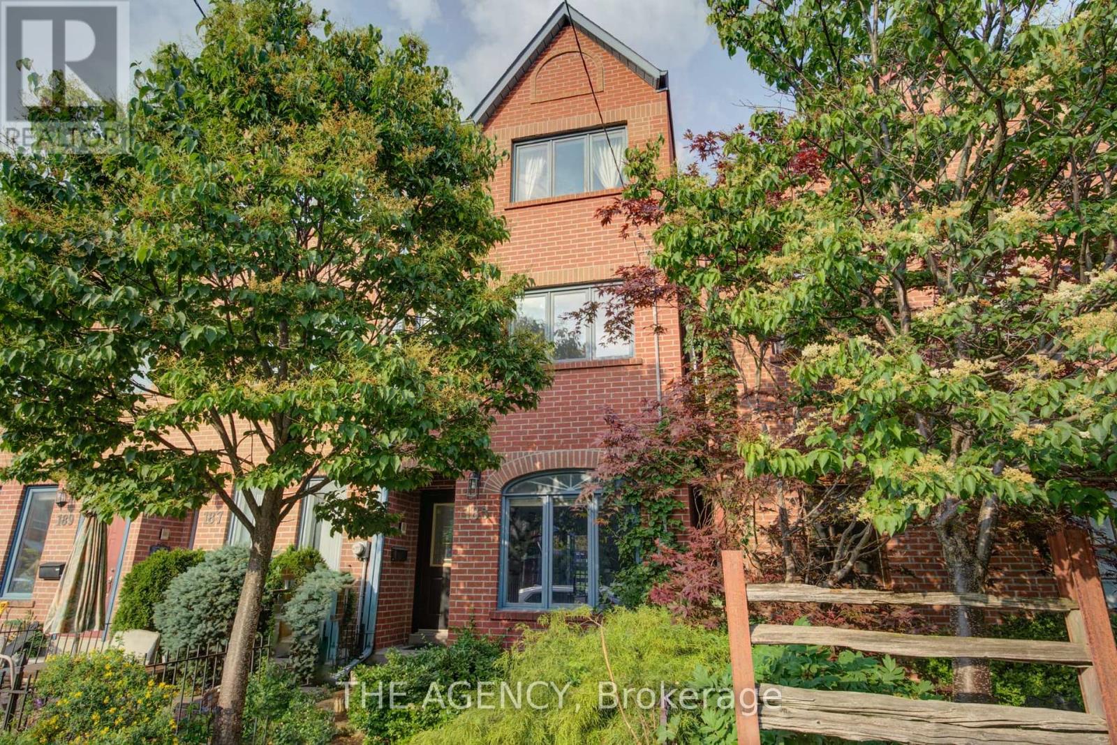 A red brick house with trees in front.