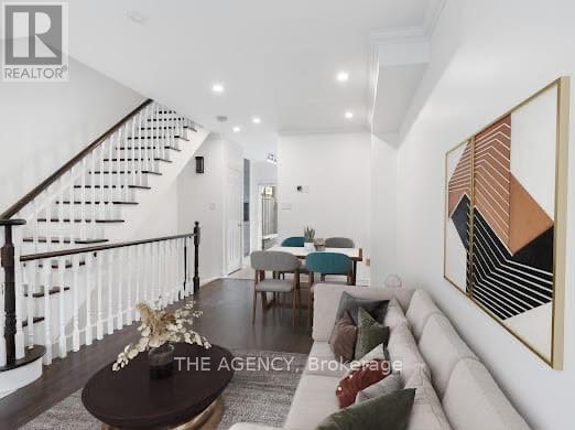 A living room with a staircase and a painting on the wall.