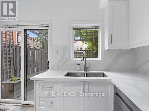 A white kitchen with a sink and a window.