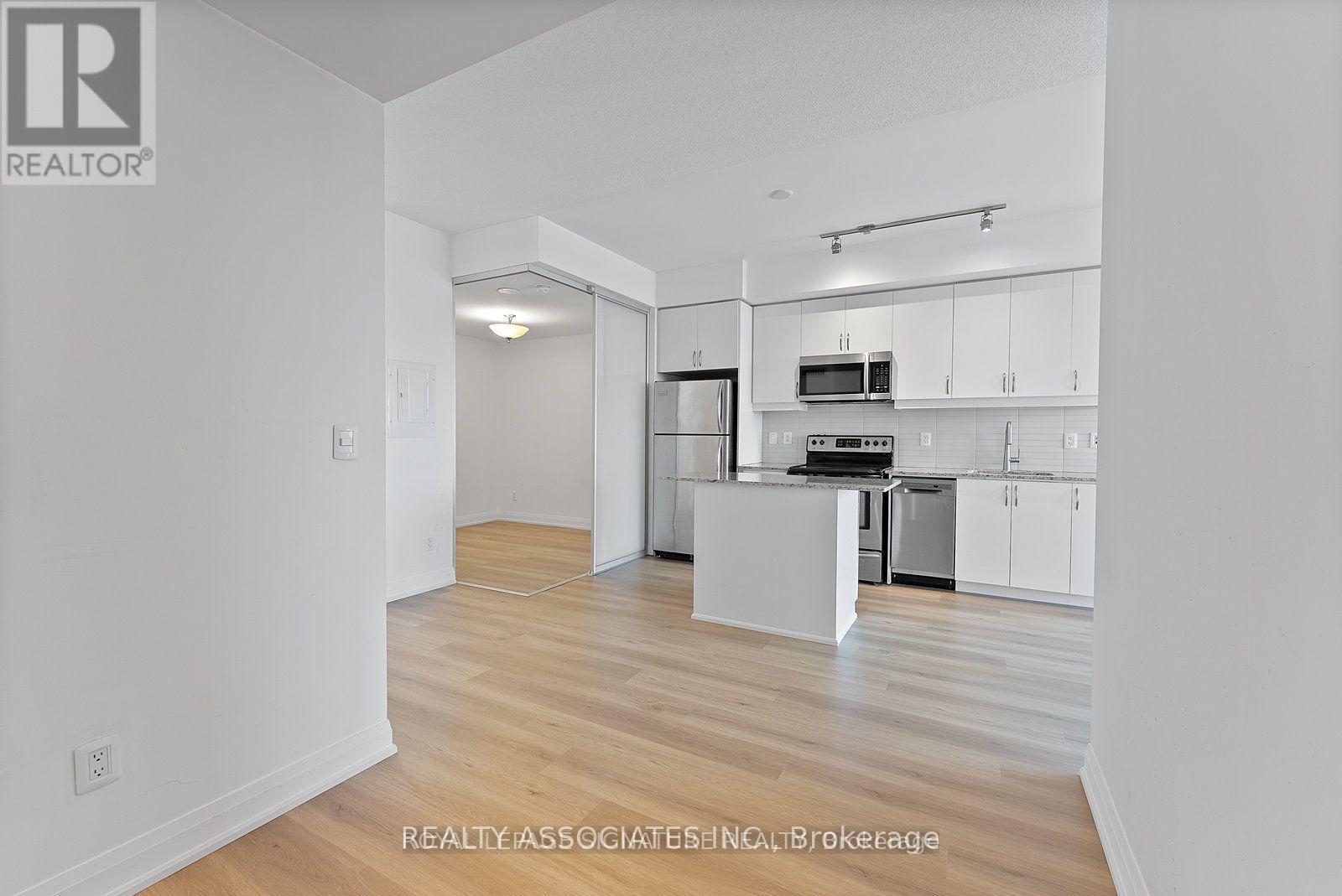 A spacious kitchen with white cabinets and a wooden floor.