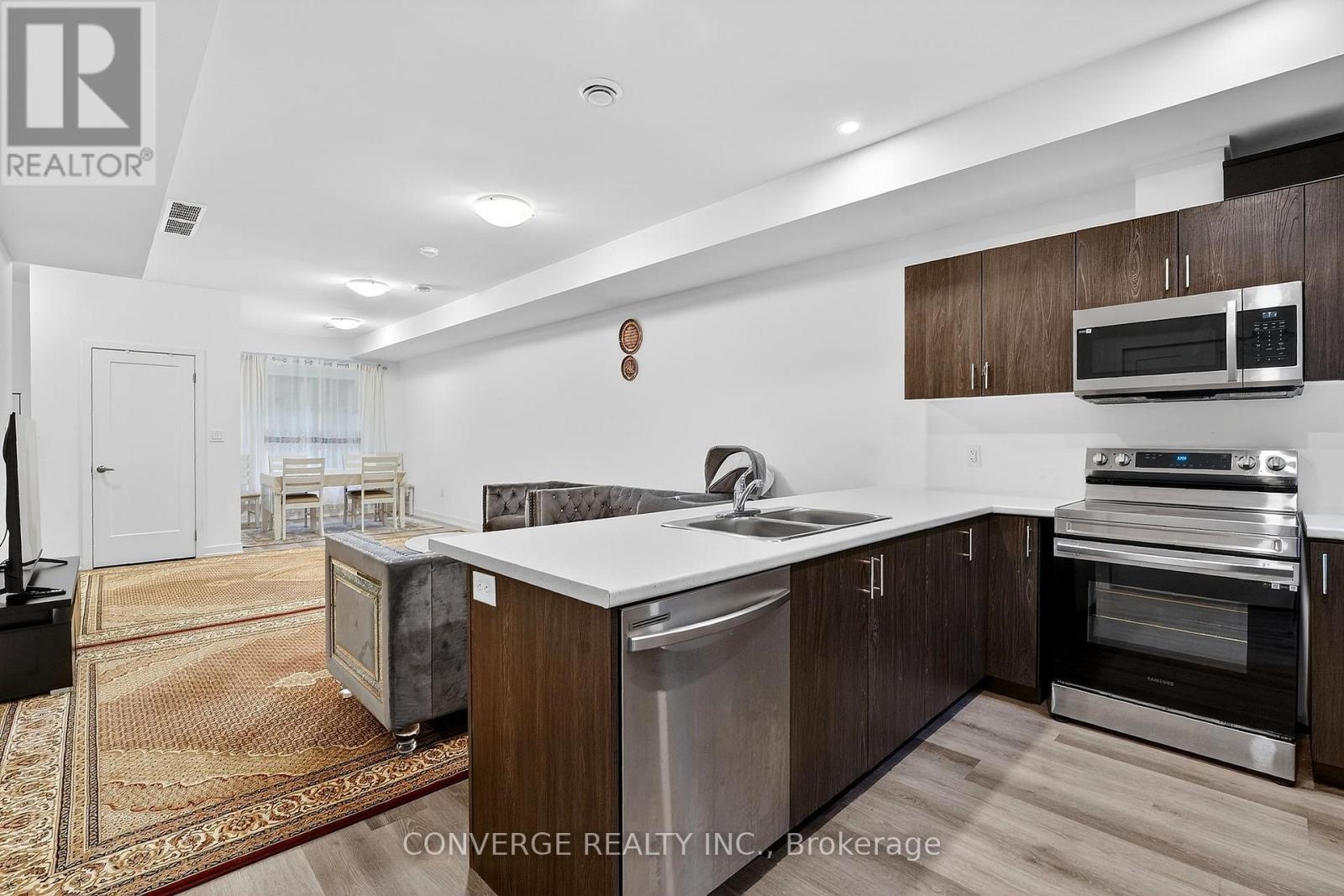 A modern kitchen with dark wood cabinets and stainless steel appliances.