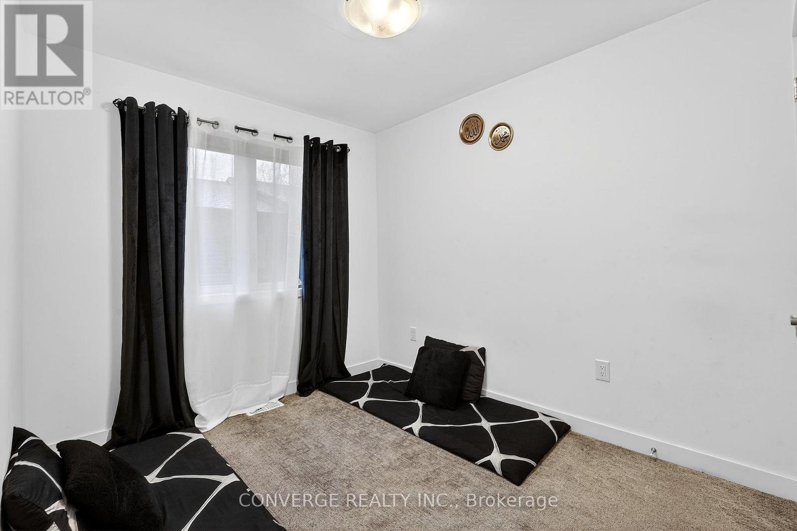 A bedroom with a large bed and a window with black curtains.