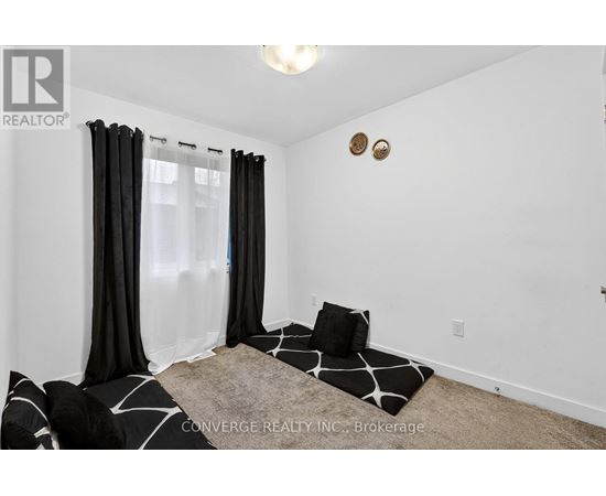 A bedroom with a large bed and a window with black curtains.