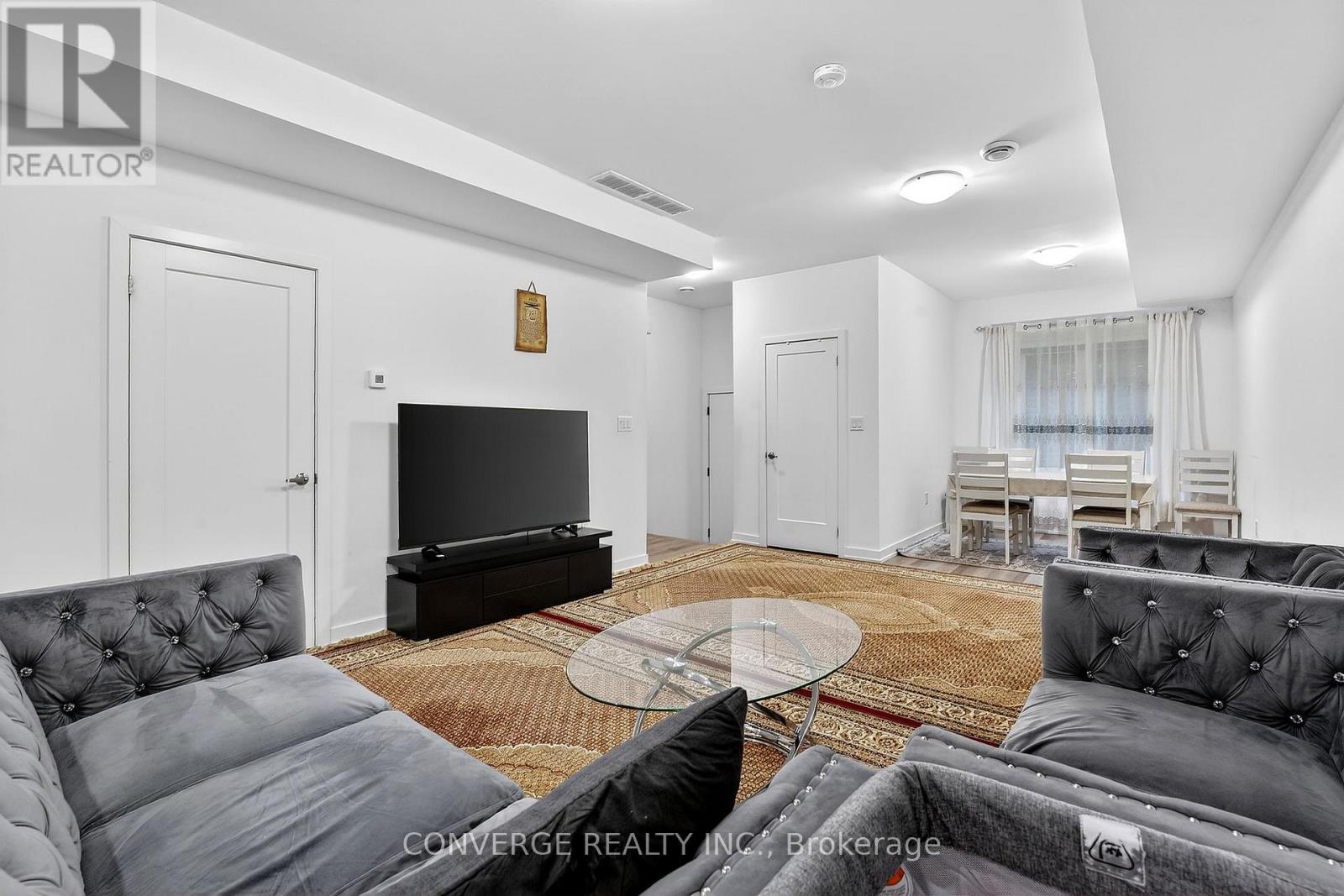 A living room with a grey couch and a glass coffee table.