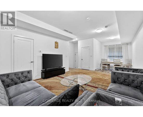 A living room with a grey couch and a glass coffee table.
