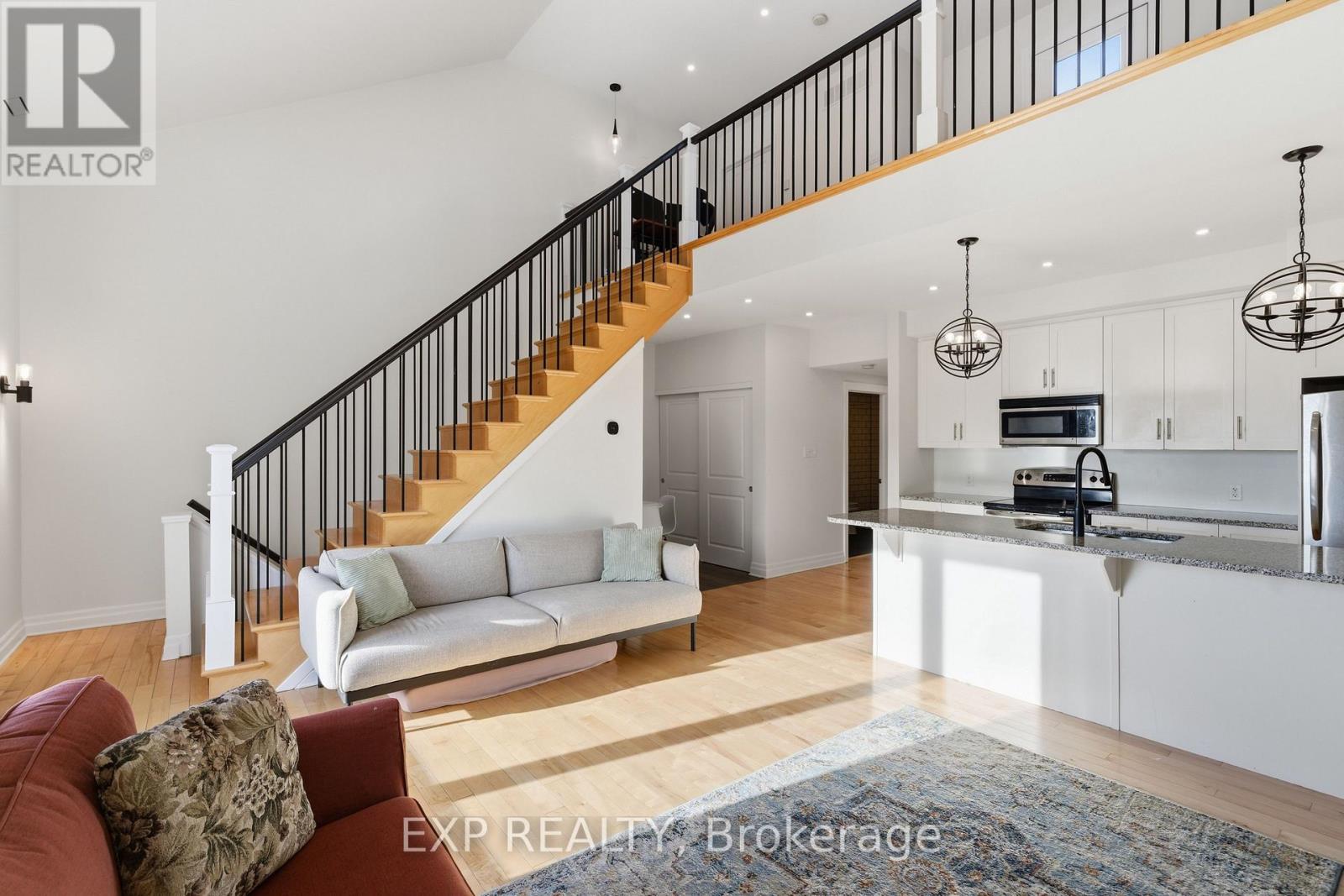 A living room with a staircase and a kitchen area.