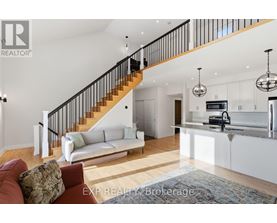 A living room with a staircase and a kitchen area.