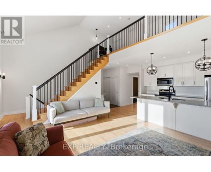 A living room with a staircase and a kitchen area.