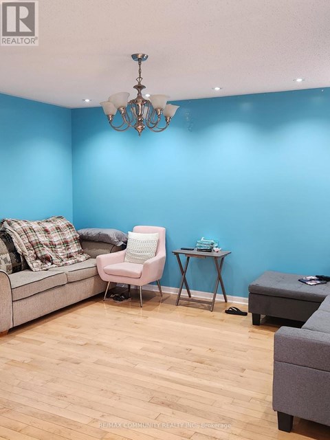 A living room with a grey couch, a pink chair, and a small table with a blue object on it.