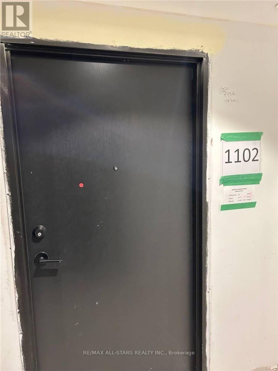 A black door with a red dot on it and a sign with the number 1102 on it.