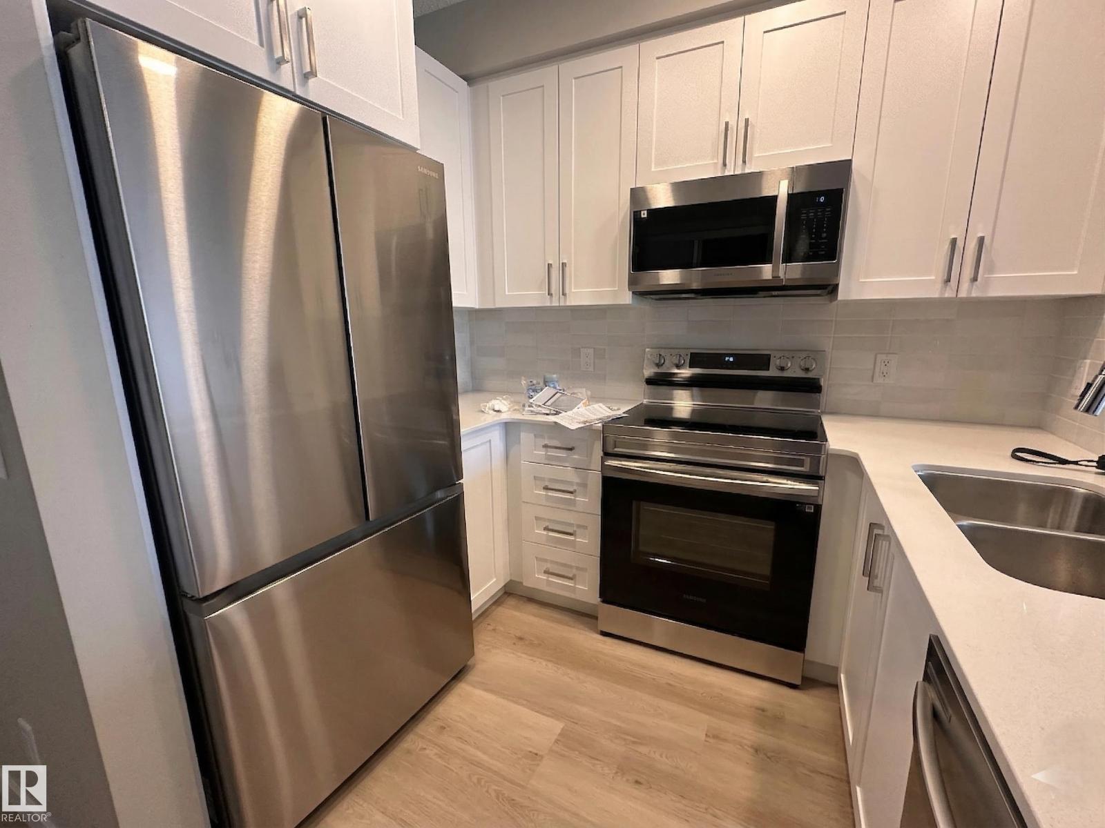 A kitchen with a stainless steel refrigerator and white cabinets.