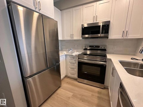 A kitchen with a stainless steel refrigerator and white cabinets.