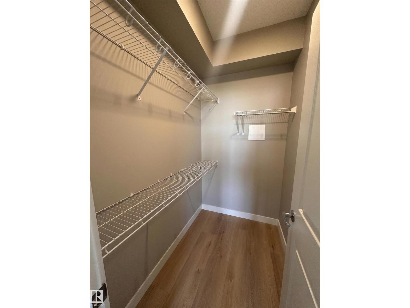 A walk-in closet with shelving and a wooden floor.