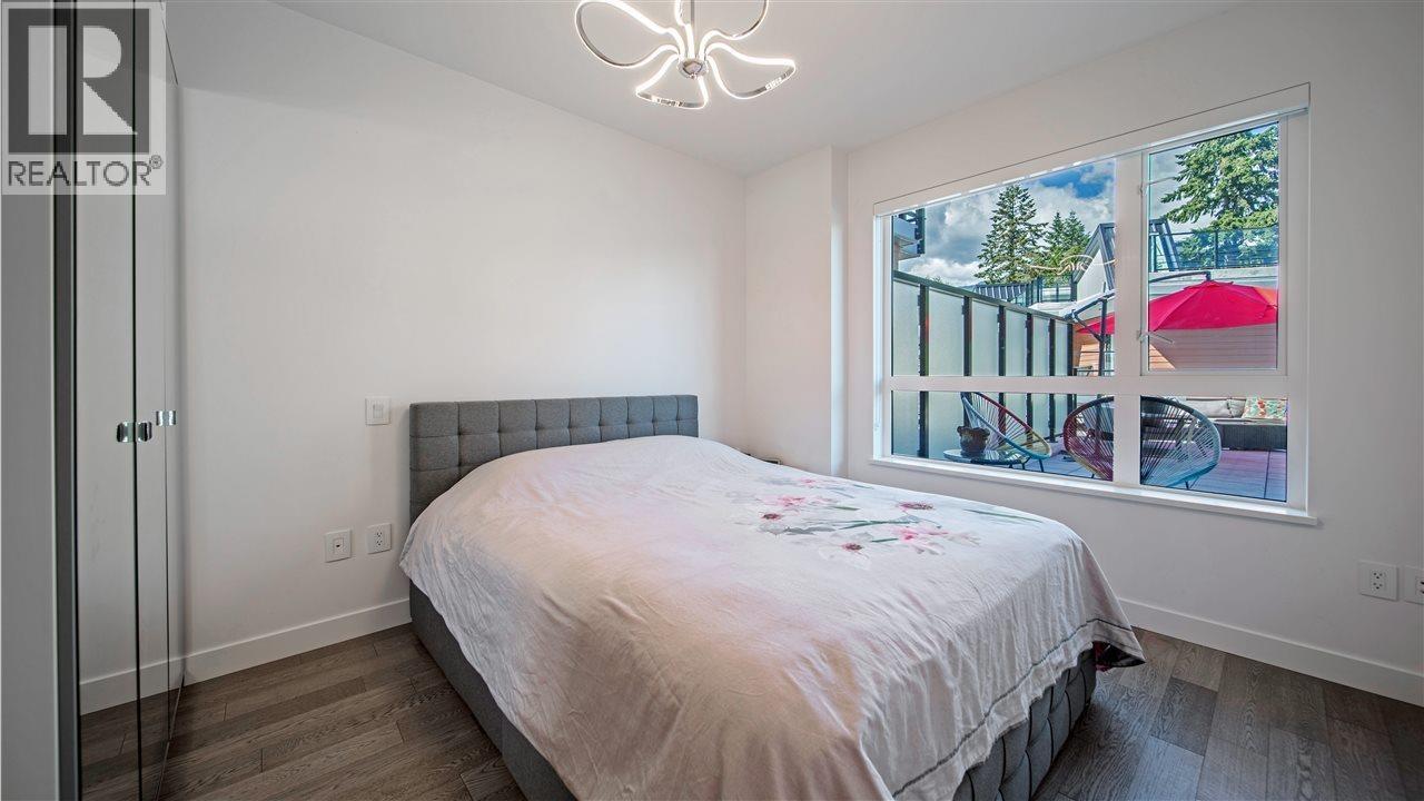 A bedroom with a large bed and a window showing a red umbrella outside.