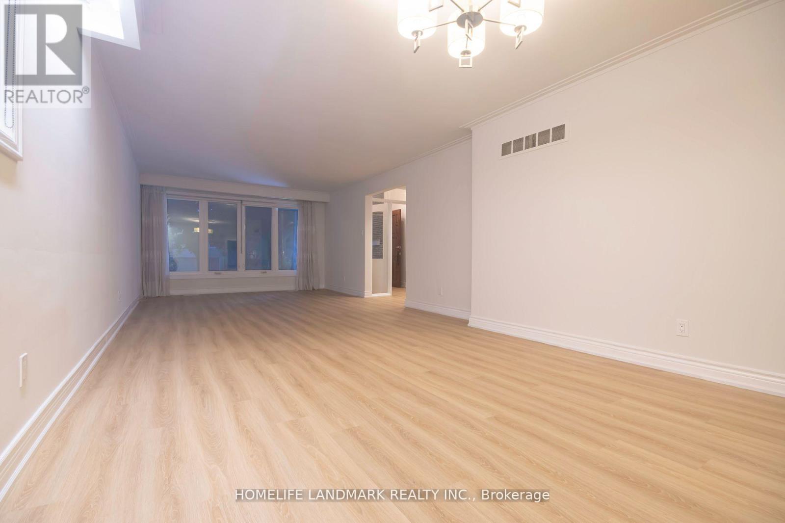 A room with wooden flooring and a chandelier.