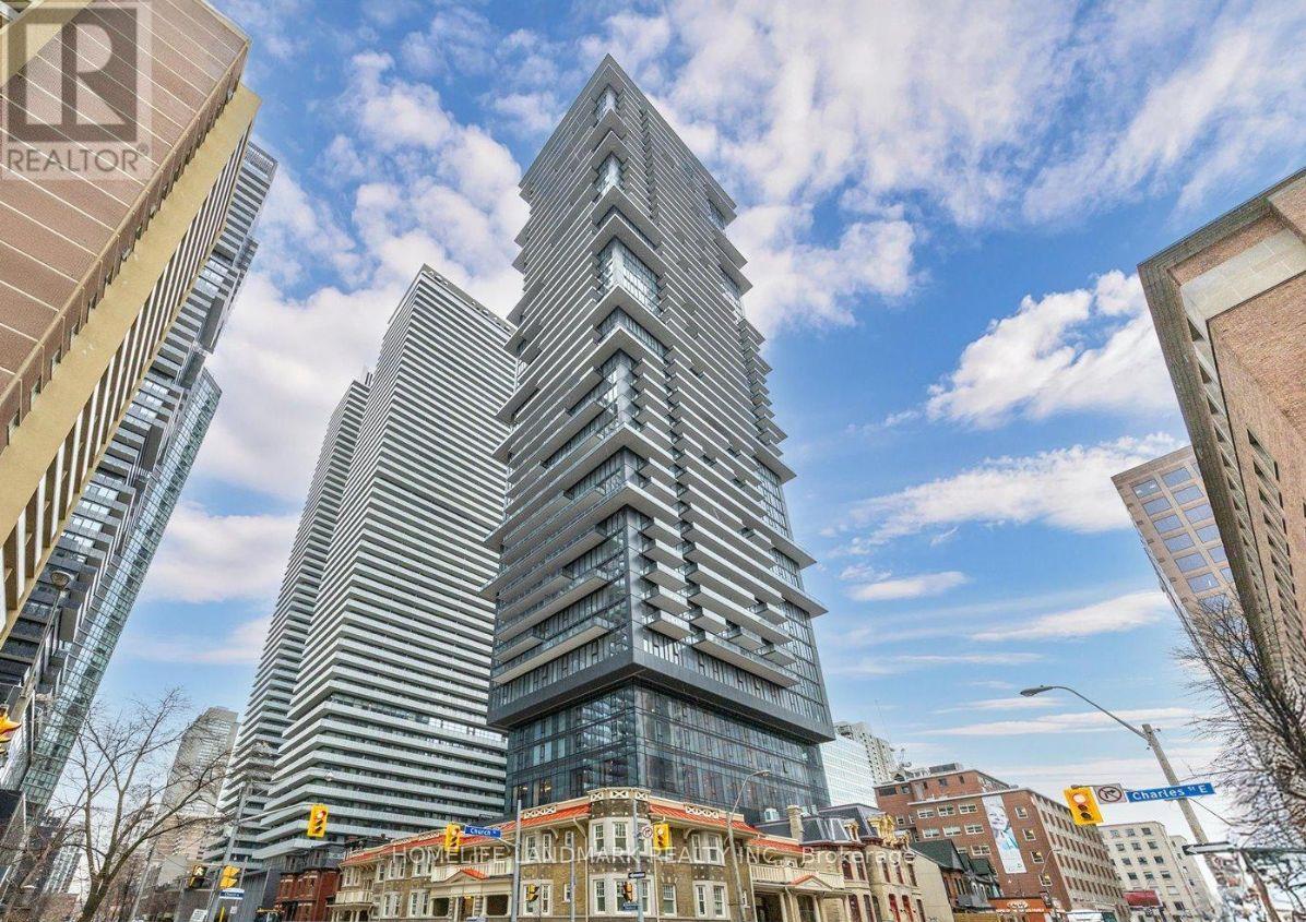 A tall building with a unique design stands in the middle of a city street.