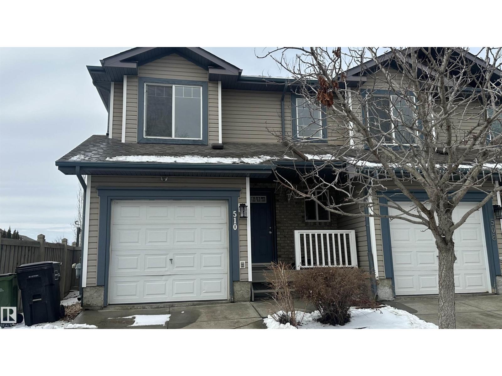 A house with a grey roof and a white garage door.