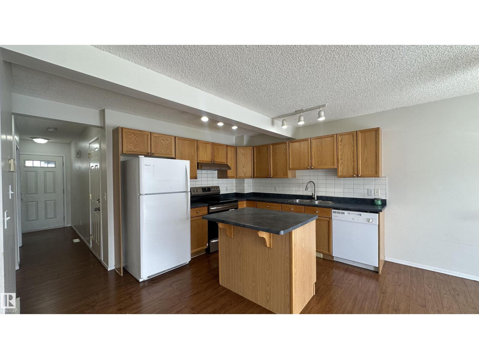 A kitchen with white appliances and wooden cabinets.