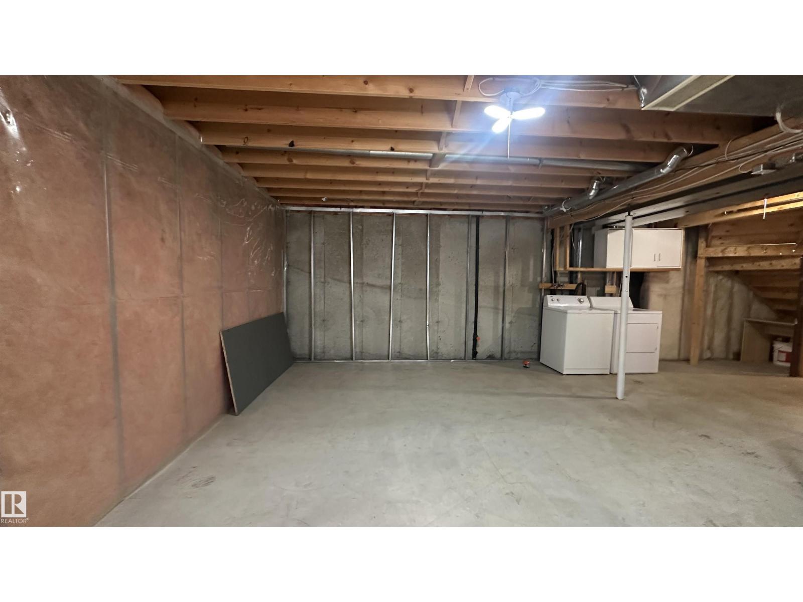 A spacious unfinished basement with a concrete floor and walls.