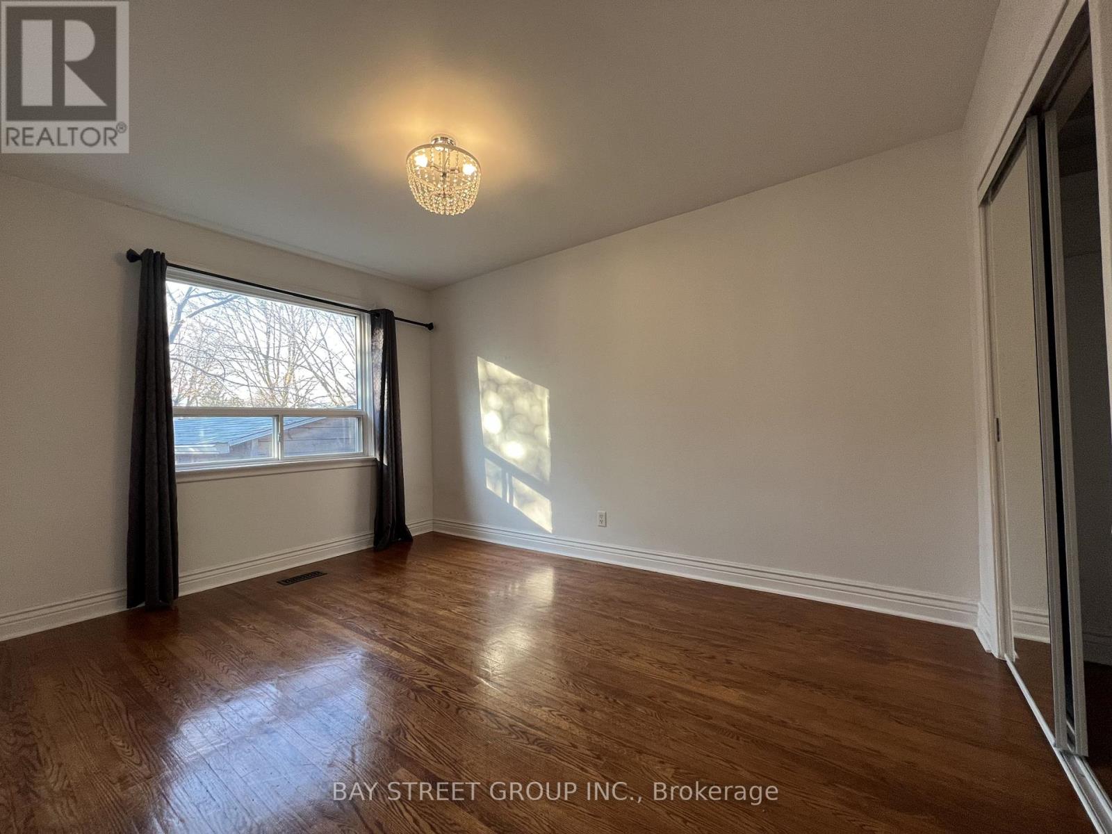A room with a wooden floor and a window with curtains.