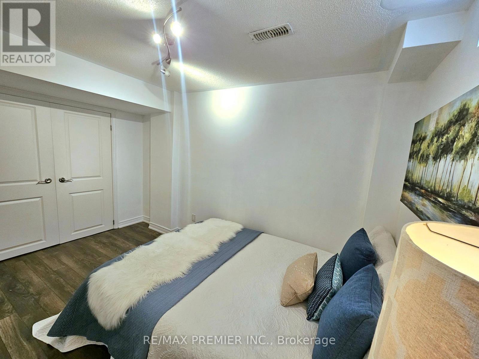 A bedroom with a bed, pillows, and a painting on the wall.