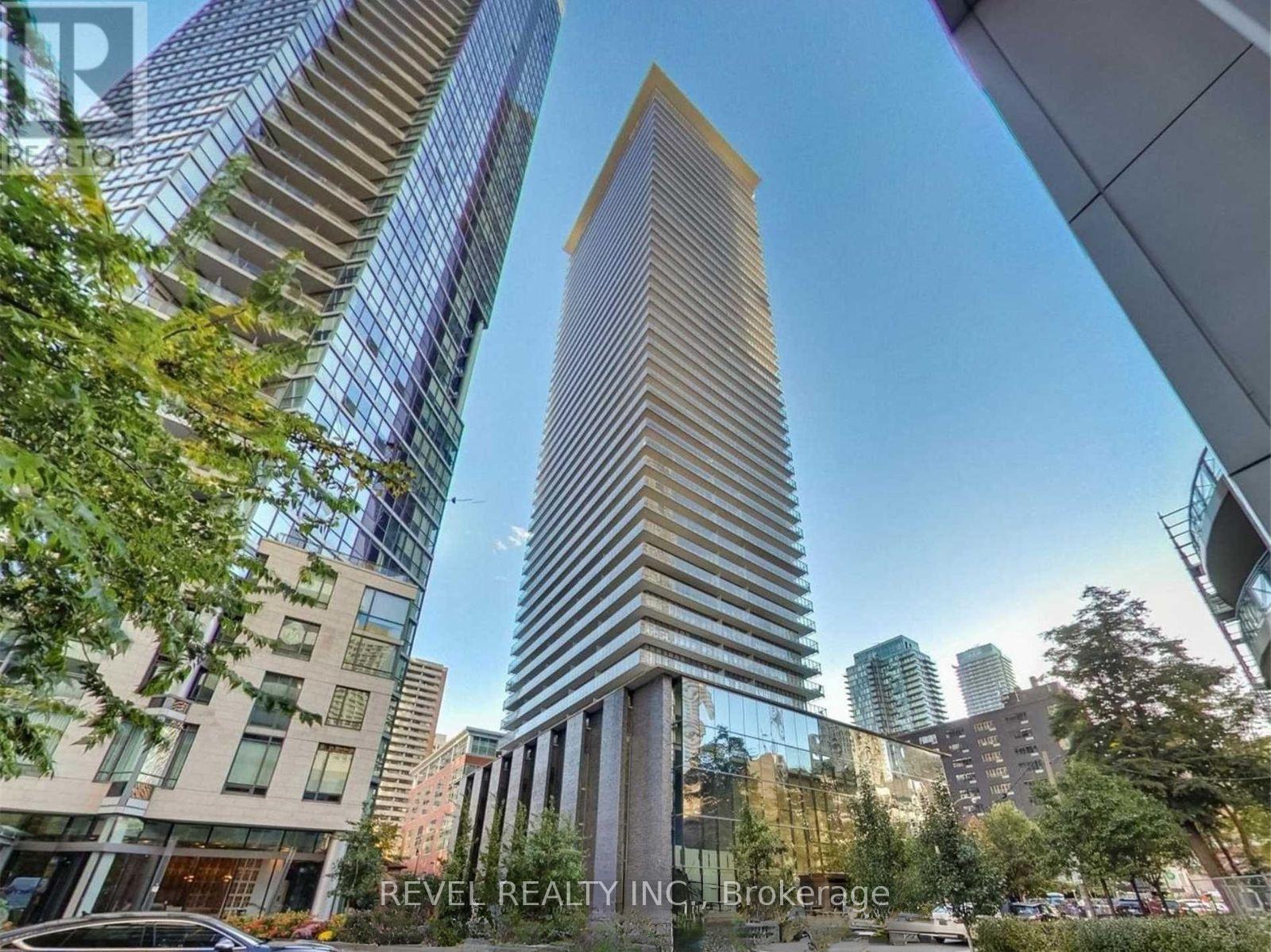 A tall building with a glass facade stands in the middle of a city street.