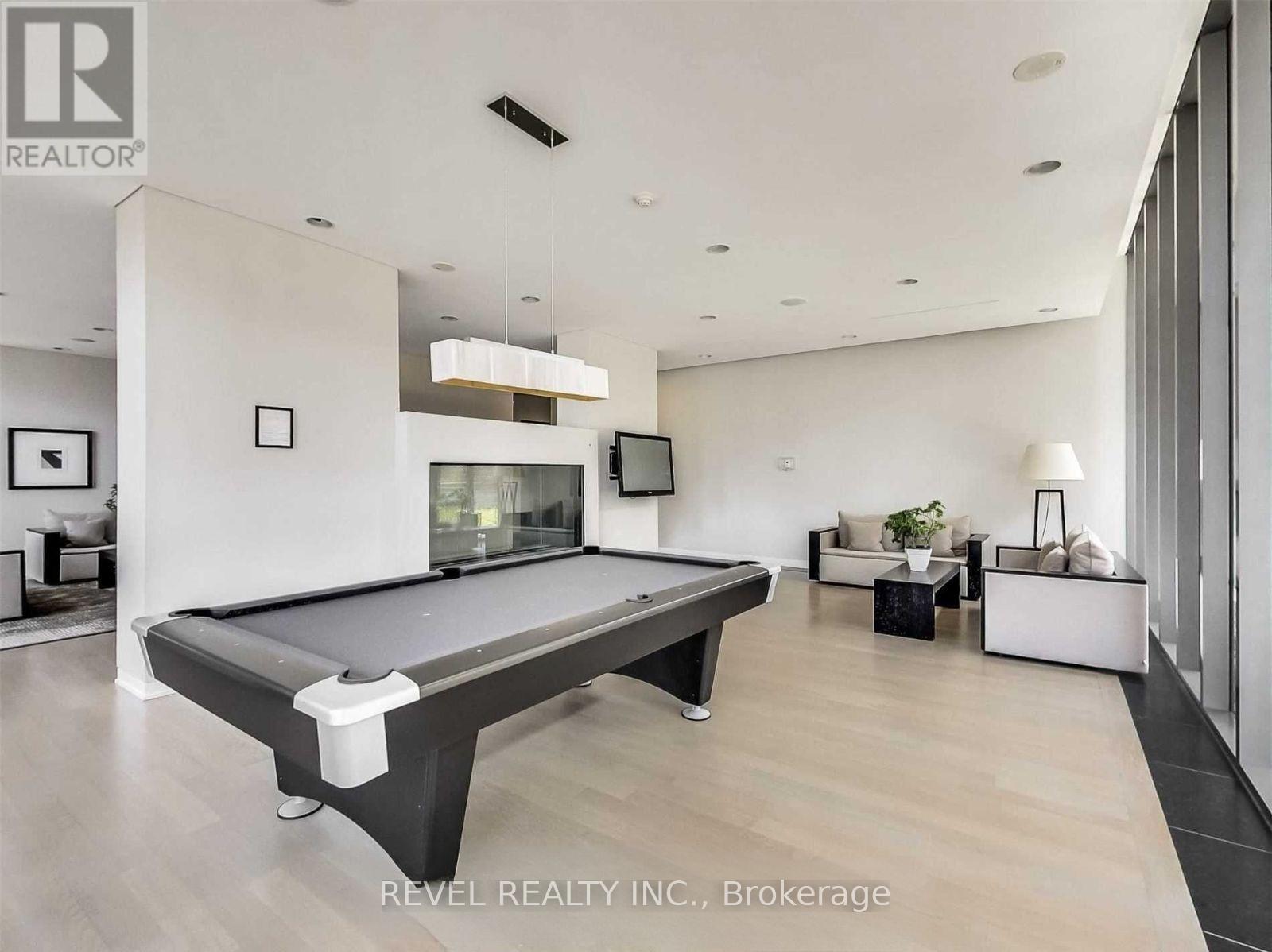 A pool table is in the middle of a well-lit room with a couch and a TV.