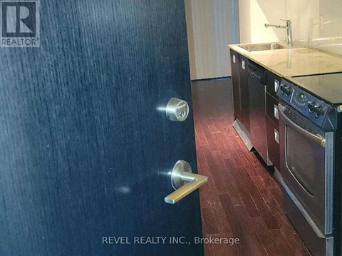 A kitchen with a black refrigerator and wooden flooring.