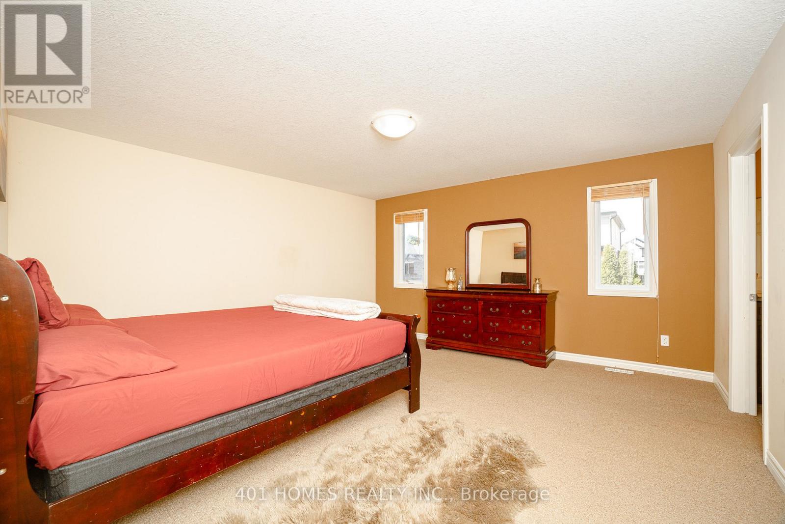 A bedroom with a red bed and a wooden dresser.