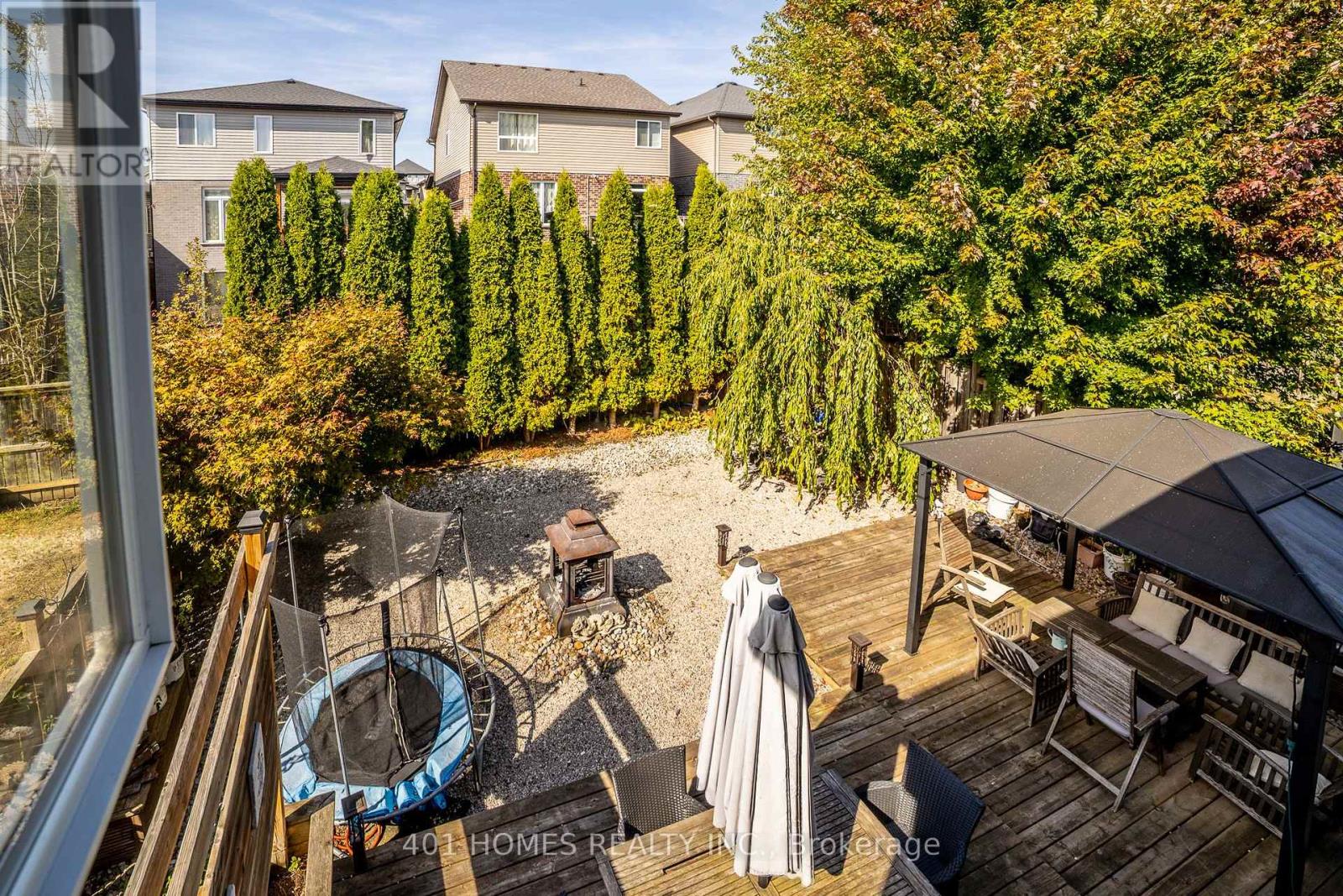A backyard with a deck, hot tub, and trees.