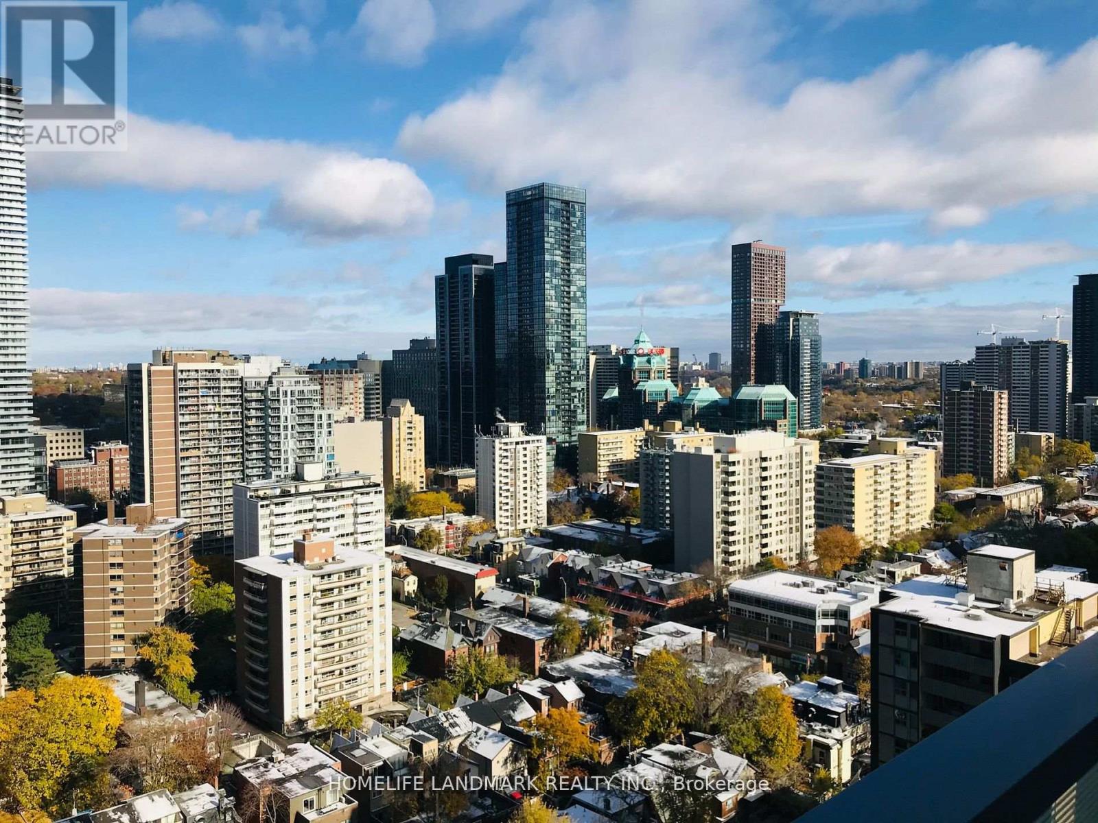 A cityscape with a mix of modern and older buildings under a partly cloudy sky.