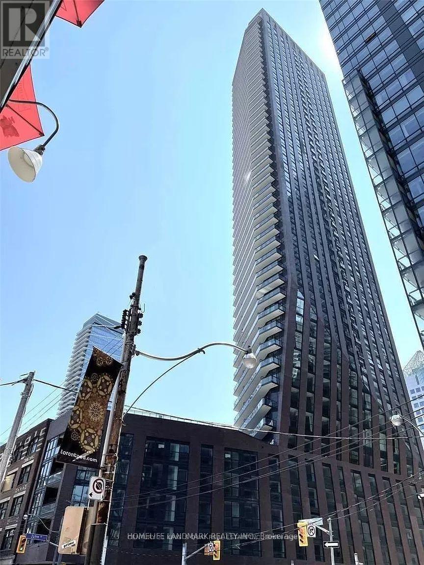 A tall building with many windows stands in the middle of a city street.