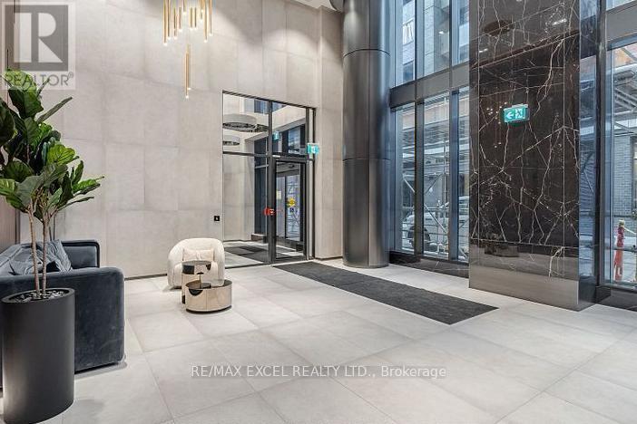 The image shows a modern office lobby with a reception desk, a potted plant, and a bench.