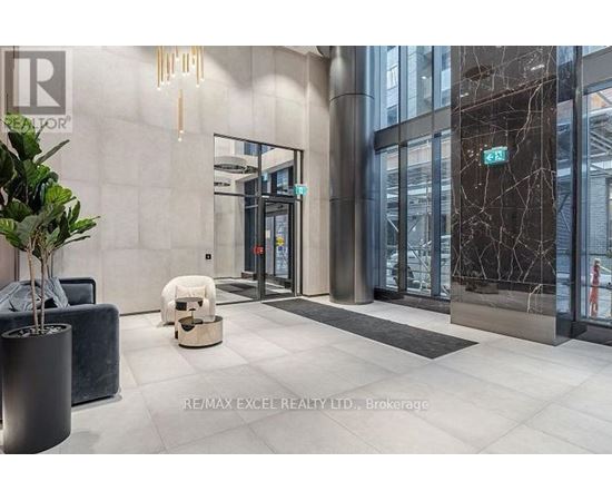 The image shows a modern office lobby with a reception desk, a potted plant, and a bench.