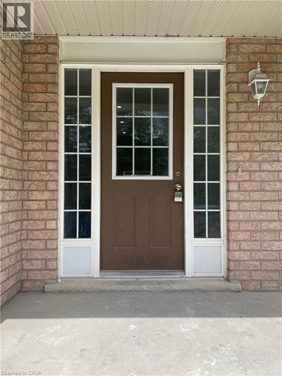 A brown door with a glass window is in front of a brick wall.