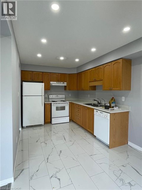 A kitchen with white appliances and wooden cabinets.