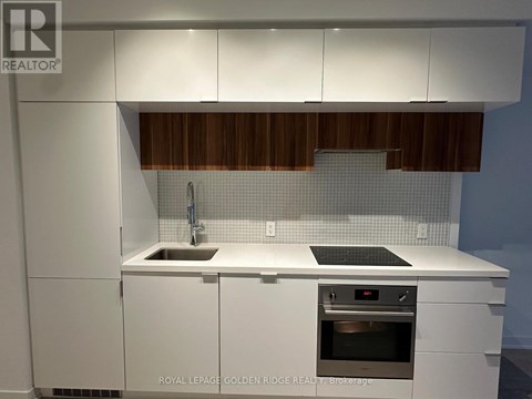 A modern kitchen with white cabinets and a wooden backsplash.