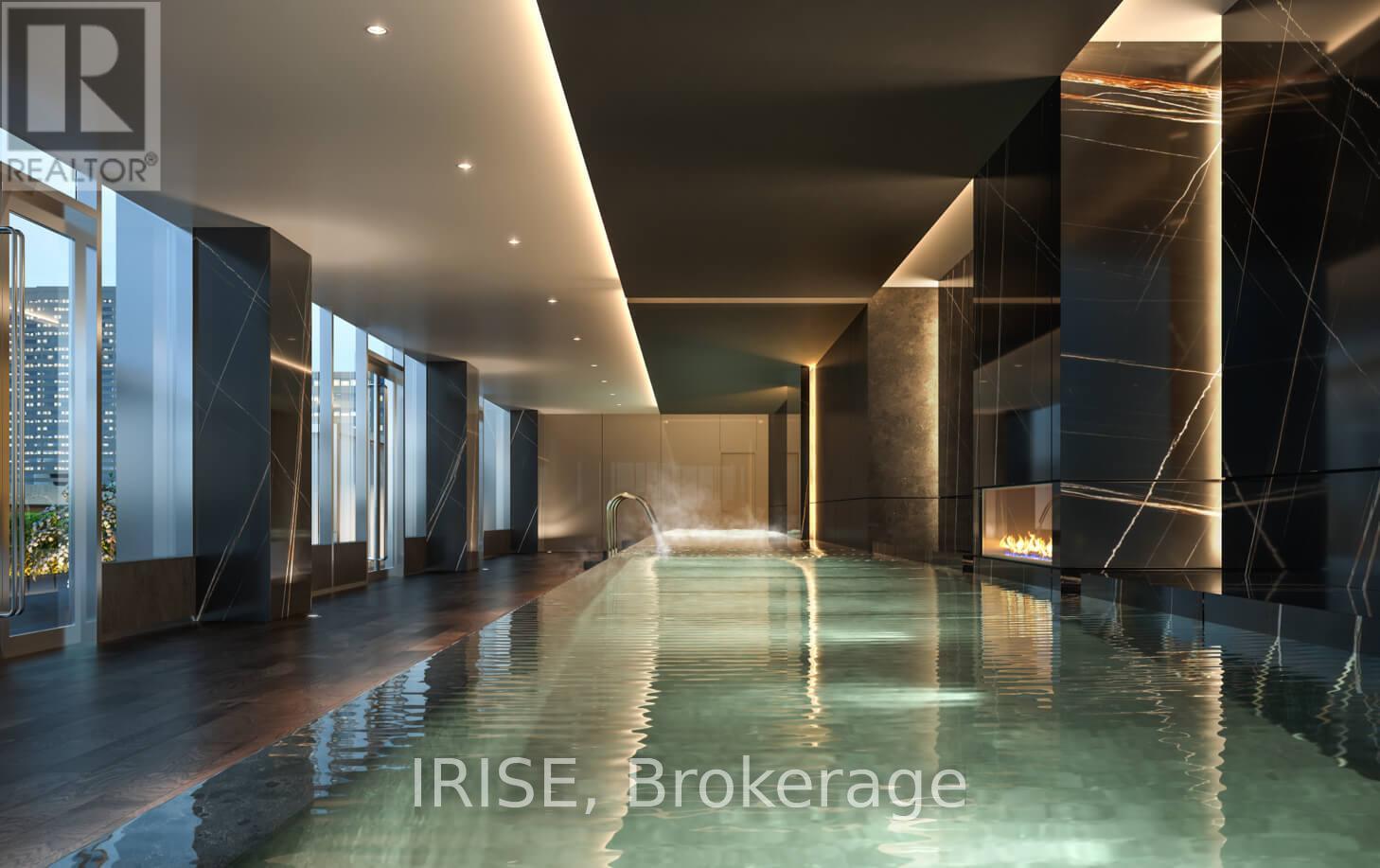 A modern indoor swimming pool with a glass wall on one side.