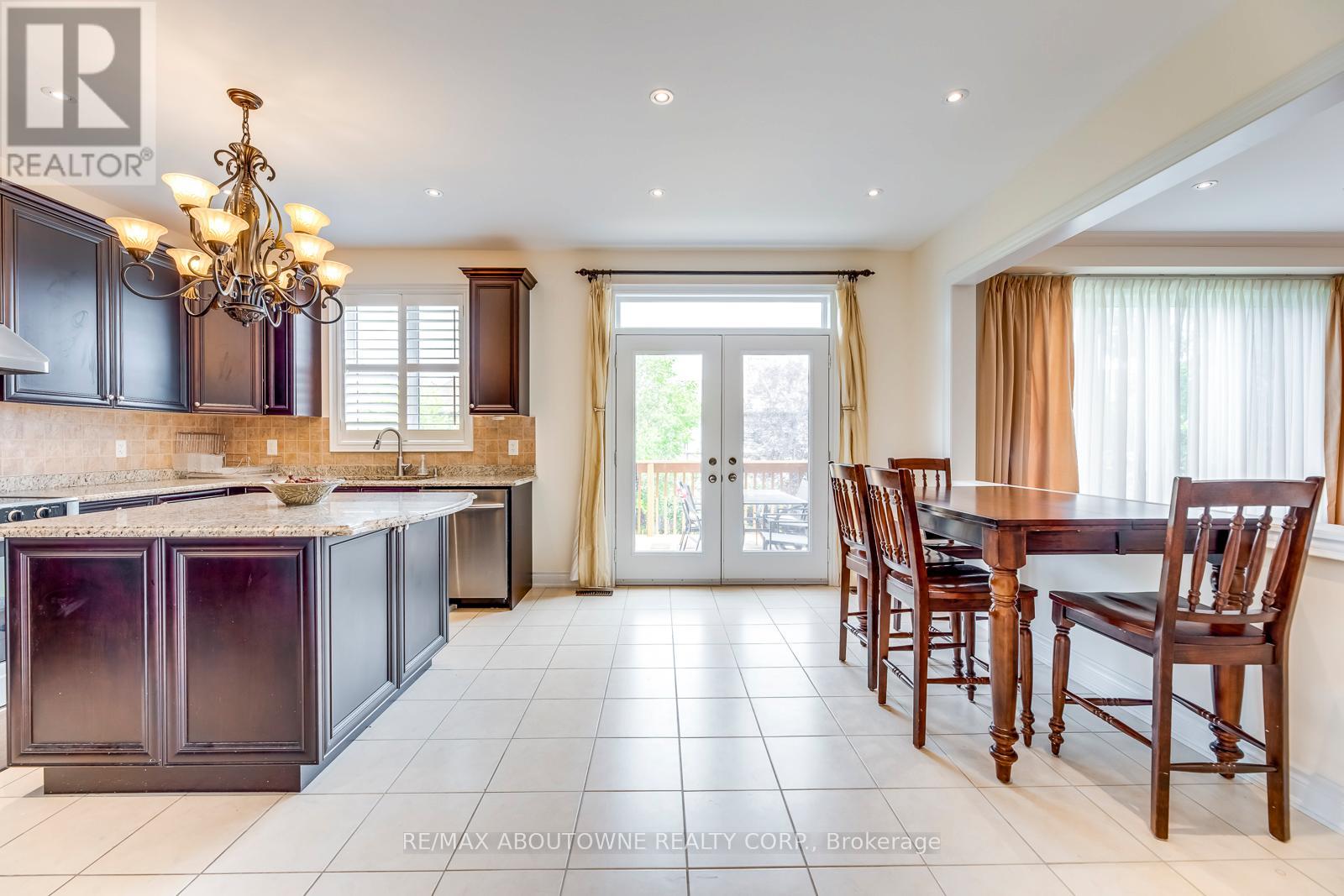 A large, well-lit kitchen with dark wood cabinets and a chandelier.