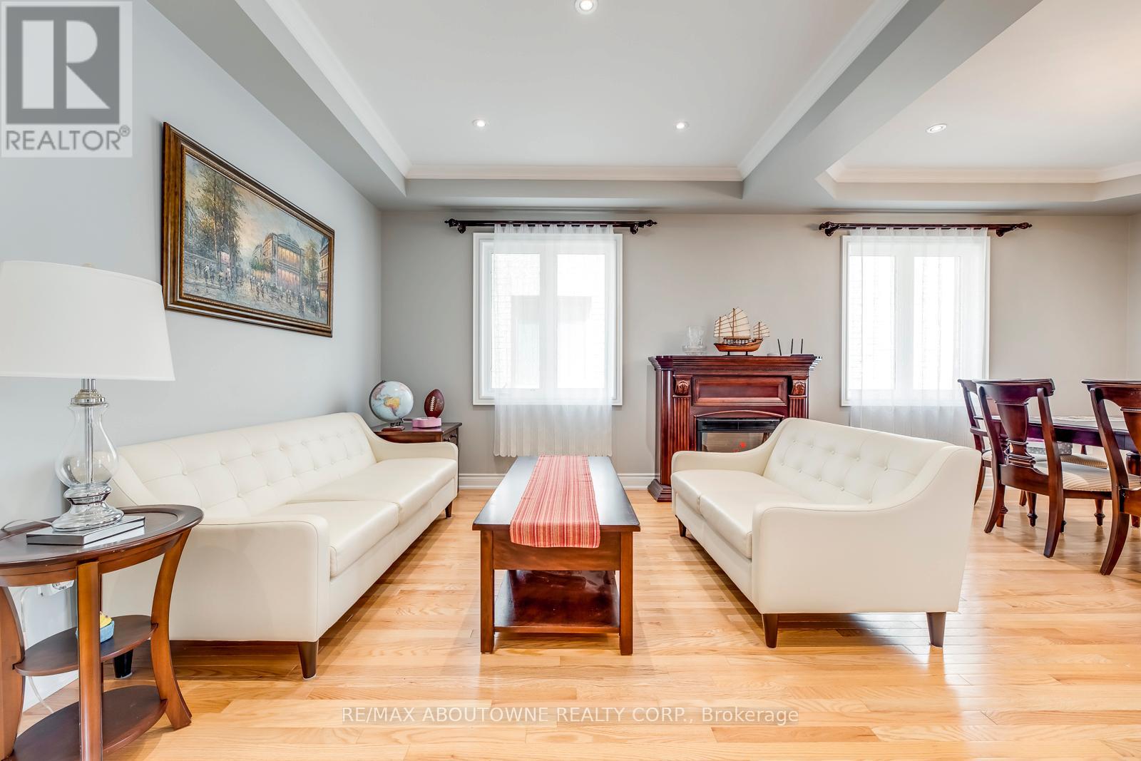 A living room with a white sofa, a wooden coffee table, and a painting on the wall.