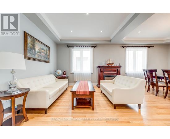 A living room with a white sofa, a wooden coffee table, and a painting on the wall.