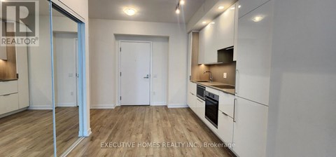 A modern kitchen with white cabinets and a wooden floor.